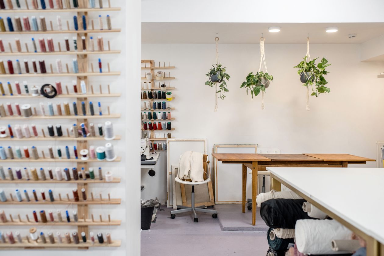Bright craft studio with a thread wall, hanging plants and work tables, a DIY storage and organization idea