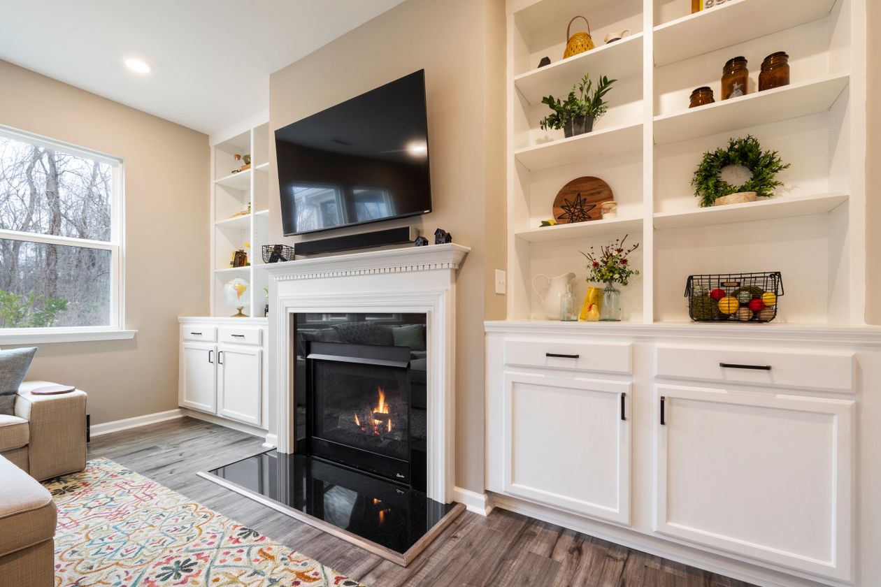 Warm living room with a fireplace, television and white built-in cabinets, a modern home storage and organization idea